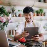 Asian male florist looking at tablet in flower shop