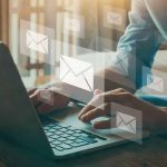 Man typing on laptop with transparent images of emails floating