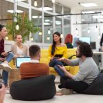 Group of young professionals sitting on floor of office discussing clients